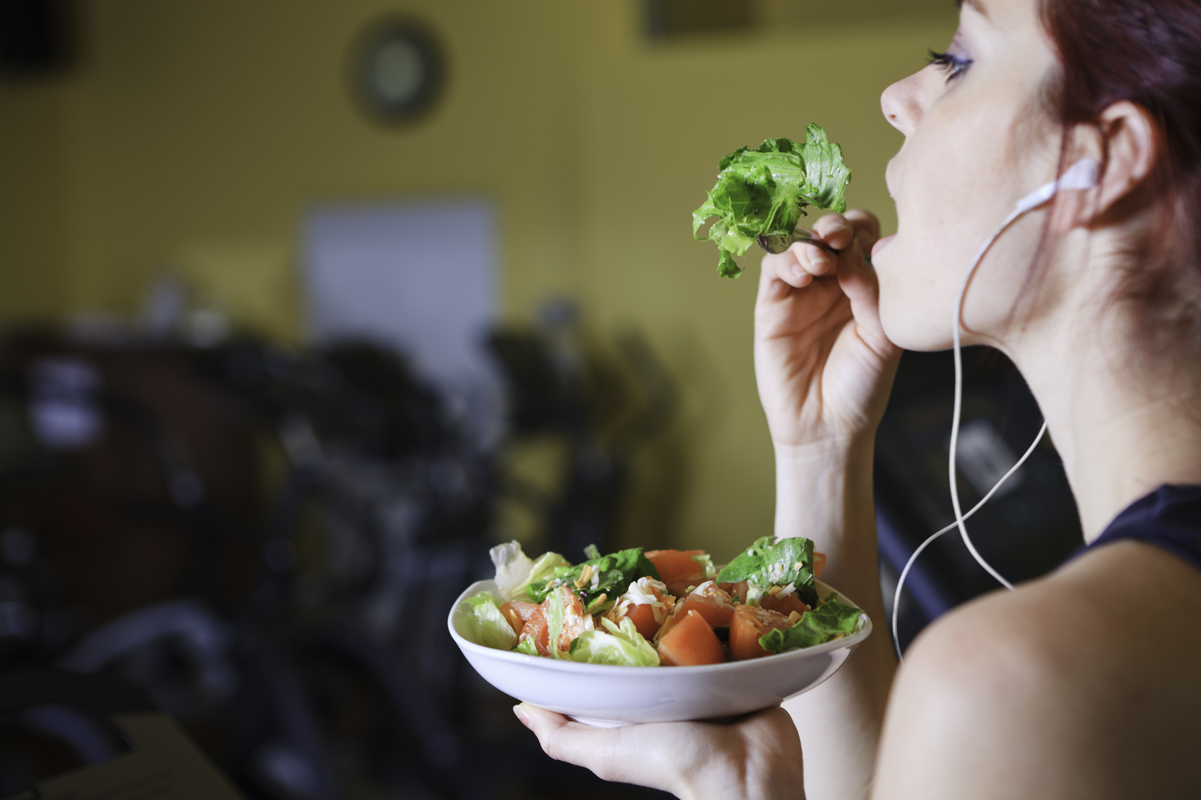 Young woman at the gym eating salad